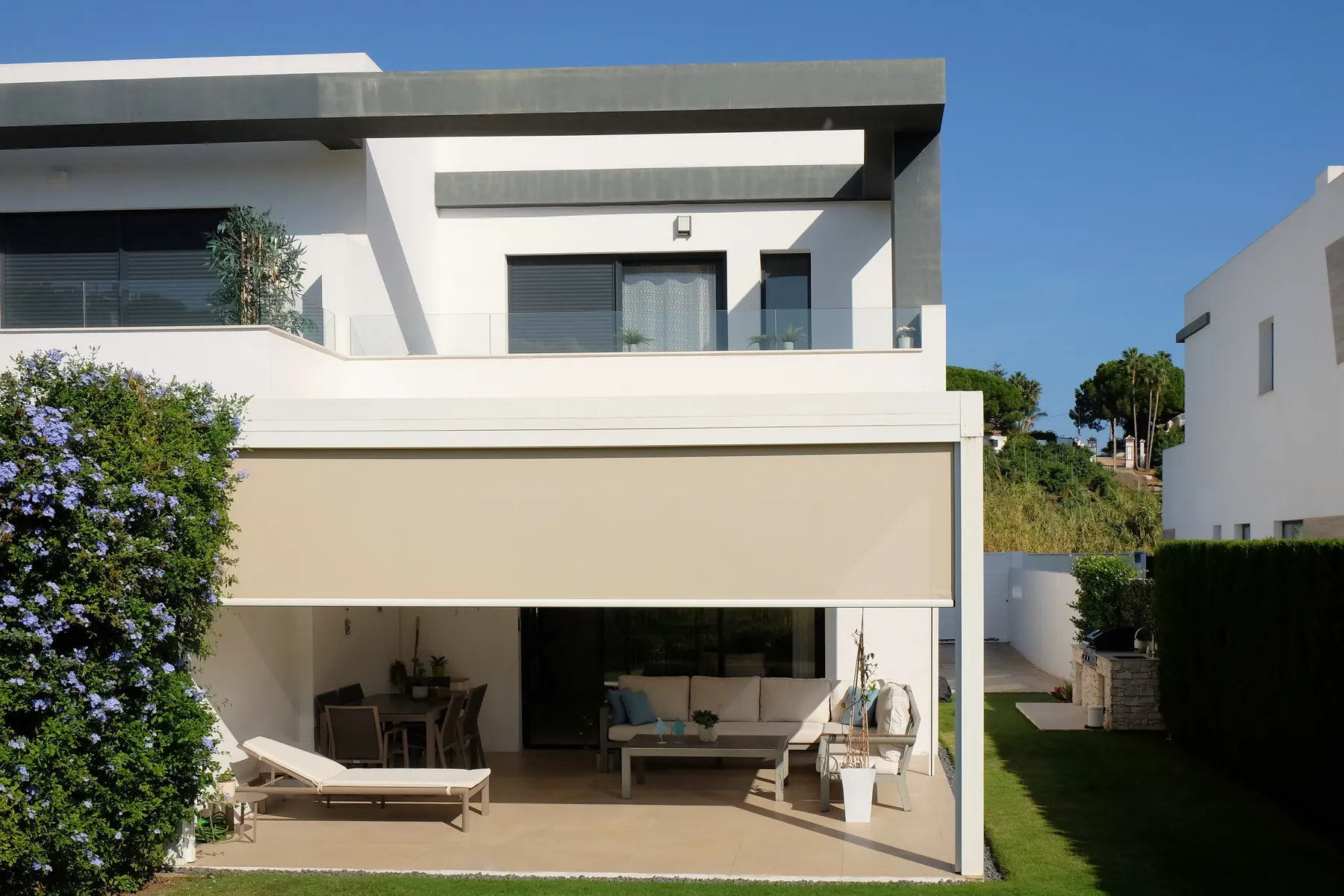 La casa desde el jardín, con la terraza bajo la pérgola y la terraza de la planta alta